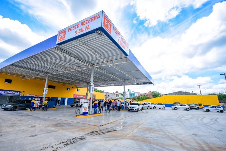 Fachada de um posto Bezerra & Silva, com cobertura azul e clientes na área de abastecimento.